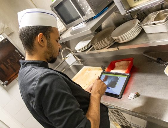 Chef recording food safety checks on a tablet in a hotel kitchen